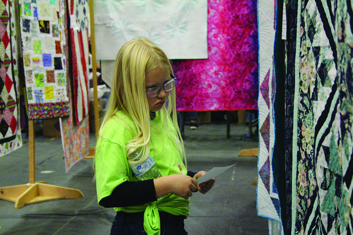 Hope Tadema, Soap Lake, carefully evaluates the entries in the Quincy Farmer-Consumer Awareness Day quilt show. Organizer Many Ottley said it was the biggest FCAD quilt show ever.