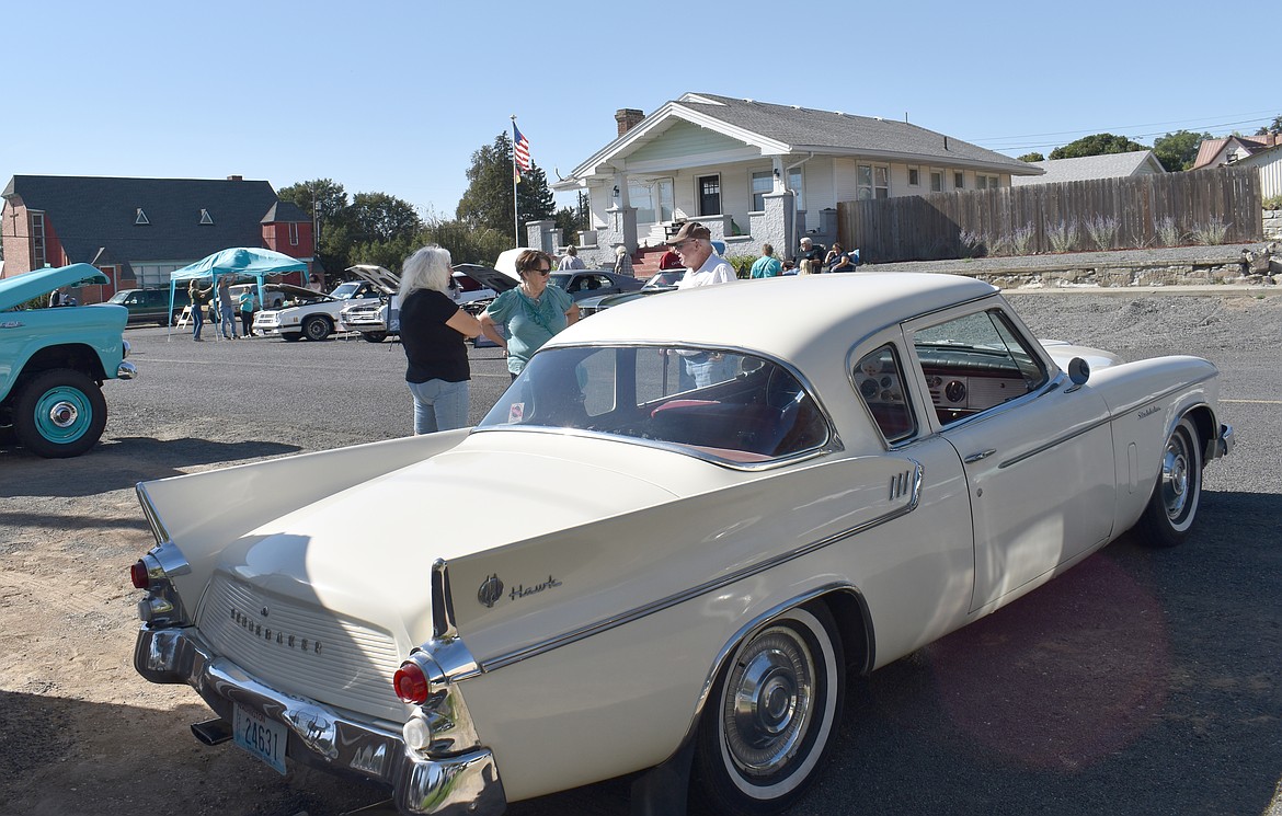 Lori Friend, left, and JoAnn Hardt, both of Marlin, listen while Gordon Stuart of Warden tells them about the 1960 Studebaker Hawk he brought to the Almira Country Fair car show Saturday.