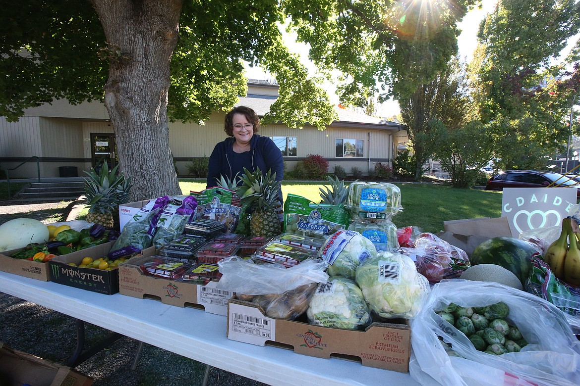 CDAIDE care counselor Candice Randall helps organize produce that was set on tables Monday morning during the PB and J Haydeners food giveaway to benefit restaurant and hospitality workers in the community.