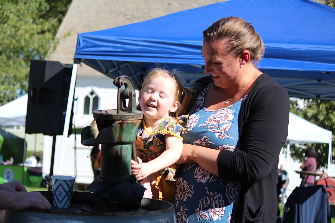 Lydia Boldman, in yellow, and her mom get water the old-school way during the harvest and culture festival sponsored by the Quincy Valley Historical Society and Museum.