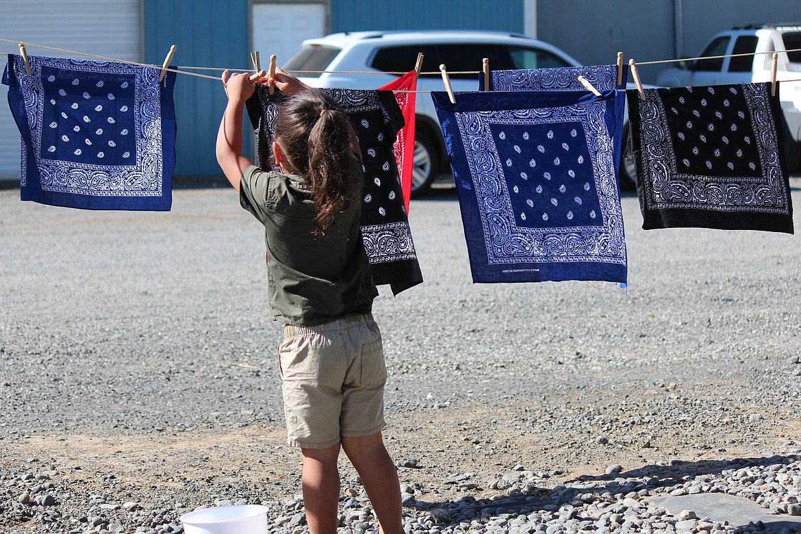 A girl attending the Celebration of Harvest and Culture dries the bandanna she washed in the washtub using the old-school way, hanging it on the clothesline.