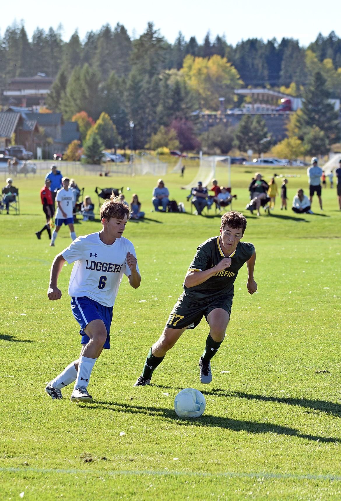 Senior midfielder Reid Alexander moves for the ball, step for step with a Libby defender. (Julie Engler/Whitefish Pilot)