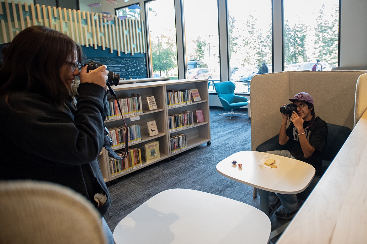 Adriana Irvine and Little Ray McDonald, members of Our Community Record photo project, photograph each other in the Bigfork Library during the REzMaDe exhibit's artist reception Wednesday, Sept. 25. (Avery Howe/Bigfork Eagle)