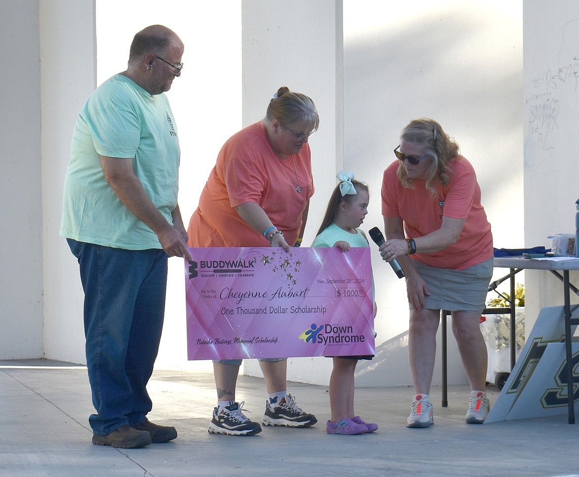 Cheyenne Aubert, joined by her parents Adam and Vanessa Aubert, receives the Natasha Hastings Scholarship from Denise Ketila at the Down Syndrome Society of Grant County Buddy Walk Saturday.