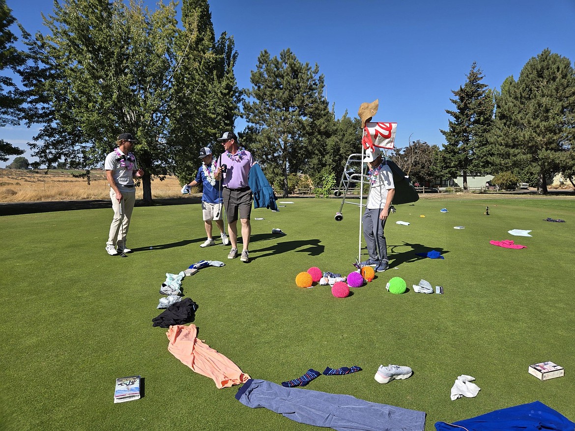 From left: Trevor West, Andy Garcia, Travis Cox and Carson Fisk drop items they’ve carried for 13 holes into the Clutter Putter at the 16th during the Dude, Where’s My Cart?! Alzheimer’s Golf Tournament Saturday.