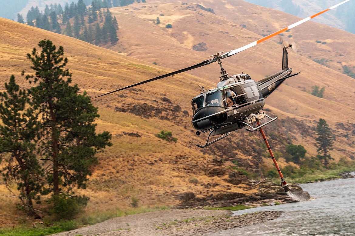 A type II helicopter with a snorkel refills its water tank from the Grand Ronde River to help contain the Cougar Creek Fire July 22. The Cougar Creek Fire charred almost 23,100 acres and was the fourth largest wildfire in Washington this year. The fire started July 15 from an undetermined cause and was contained on Oct. 1, according to InciWeb.