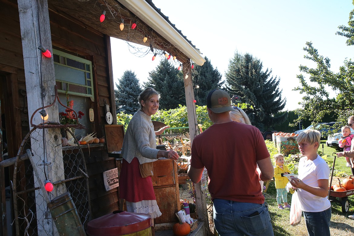 Prairie Home Farm owner Linda Swenson gives Brennon Pickett and his son, Uriah Pickett, 9, goodie bags Wednesday morning. A 20th birthday celebration will be held at the farm from noon to 5 p.m. Sunday.