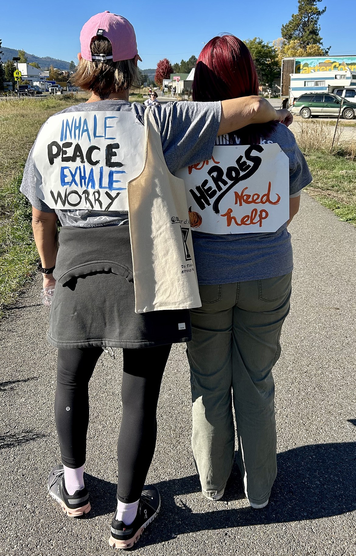 Two participants in the 2023 NAMI Far North Walk show the signs they created as they head out on the walk along the Sandpoint-Dover Community Trail. This year's walk kicks off today at 10 a.m.