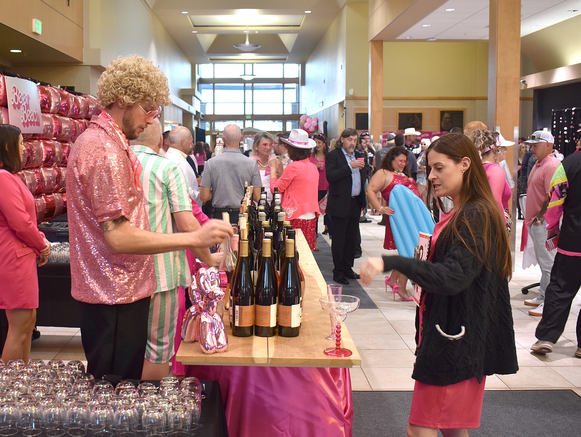 Boys & Girls Club Board Member Trace Stephens pours wine for Jamie Olsen at the club’s Barbie-themed fundraiser auction and banquet Saturday.