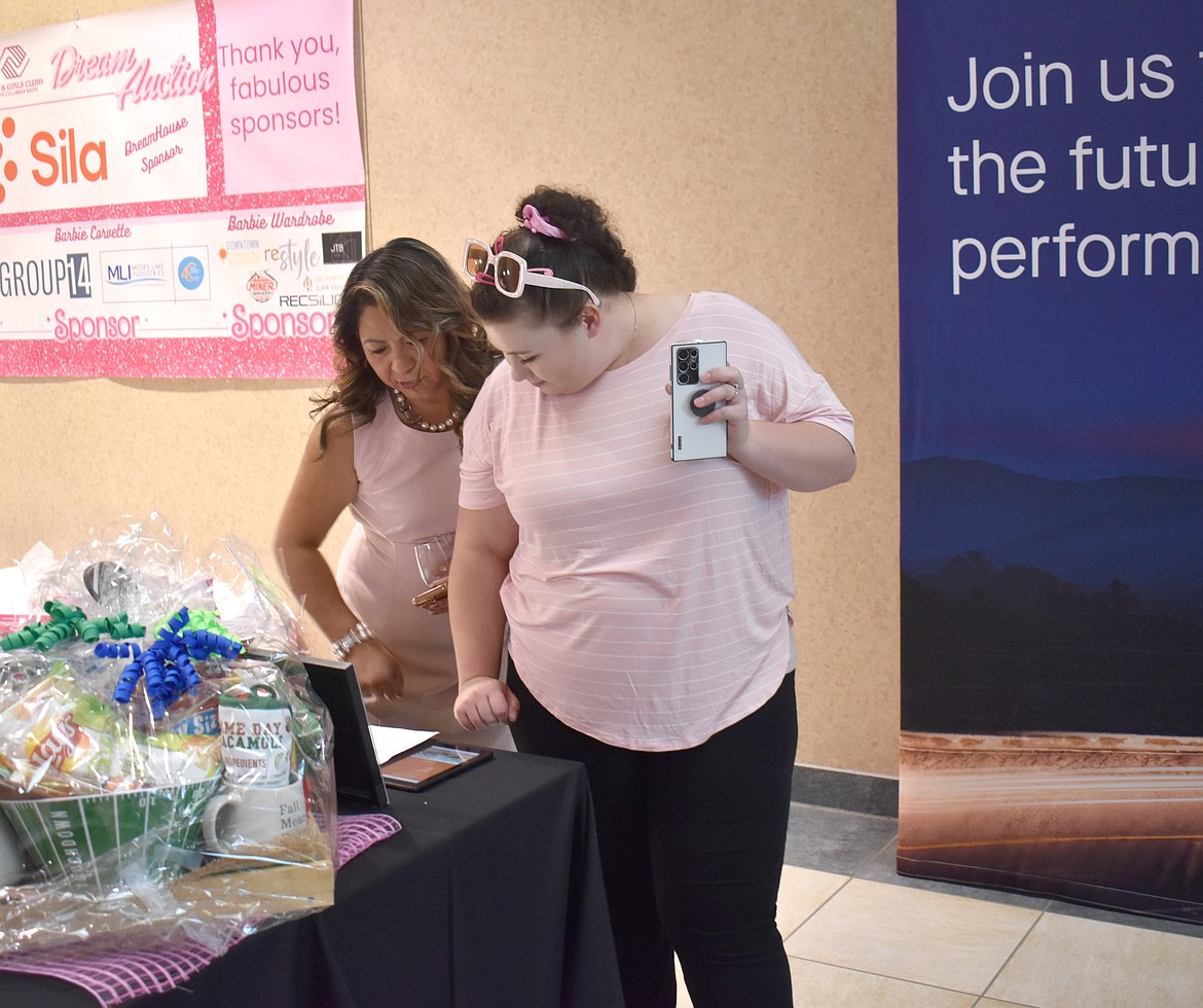 Perlita Owen, left, and Bree Lantis look over the silent auction items at the Boys & Girls club banquet Saturday