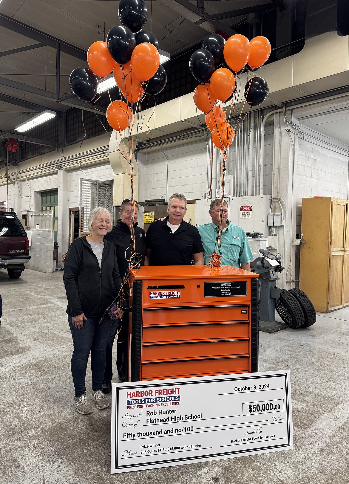 Flathead High School automotive teacher Rob Hunter is surrounded by family after being surprised with a Harbor Freight Tools for Schools $50,000 prize on Tuesday, Oct. 8, 2024, in the auto shop. Pictured left to right is his mother Karol, wife Vicki, Rob, and brother Ryan, (Hilary Matheson/Daily Inter Lake)