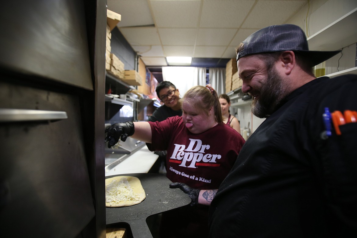 Karsyn Leffler, 19, sprinkles fresh cheese onto dough under the supervision of Wonder Crust Pizza partner/owner Nick Stafford during a Secondary Transition Education Program work session Tuesday morning at Wonder Crust Pizza in Coeur d'Alene.