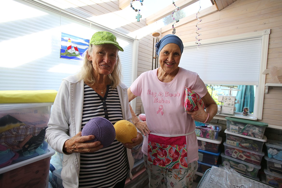 Elaine Kimball, who continues to knit Knitted Knockers following her daughter's death due to breast cancer, holds a pair of the knit prostheses Tuesday while Bag and Boob Babes Northwest Director Sheila Wayman models a drain apron and matching pillow.