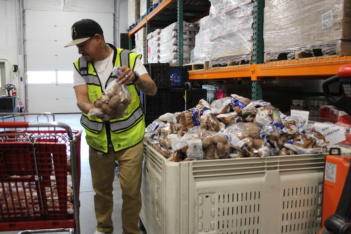 Moses Lake Food Bank Warehouse Manager Ricky Padron sorts potatoes for distribution at the food bank Wednesday.