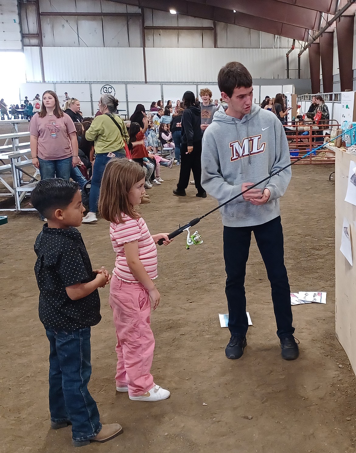 Moses Lake High School student Colton Lucero helps first-grader Averie Talavera cast her line at Lucero’s display at First Grade Farm Day Wednesday. The presentation taught the children how to tell the difference between saltwater and freshwater fish.