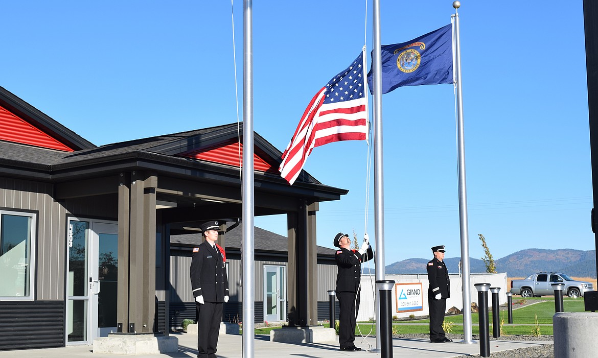 Honor Guard members perform the ceremonial raising of the flags at Fire Station 3 Saturday morning.