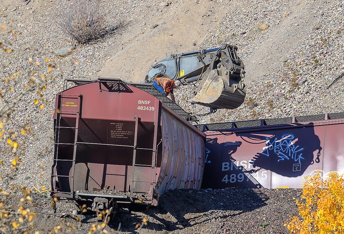 A worker looks to affix a chain to a derailed car on the border of Glacier National Park Saturday. (Chris Peterson photo)