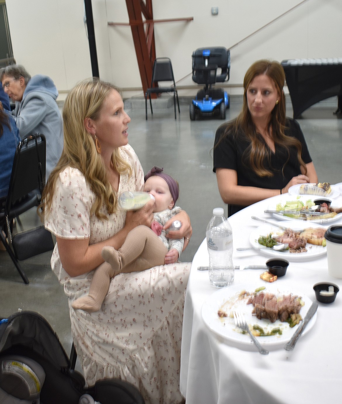 Caitlin Graves, left, chats with Micah Hoiland while she feeds 6-month-old Josie at the Crossroads Resource Center banquet Saturday.