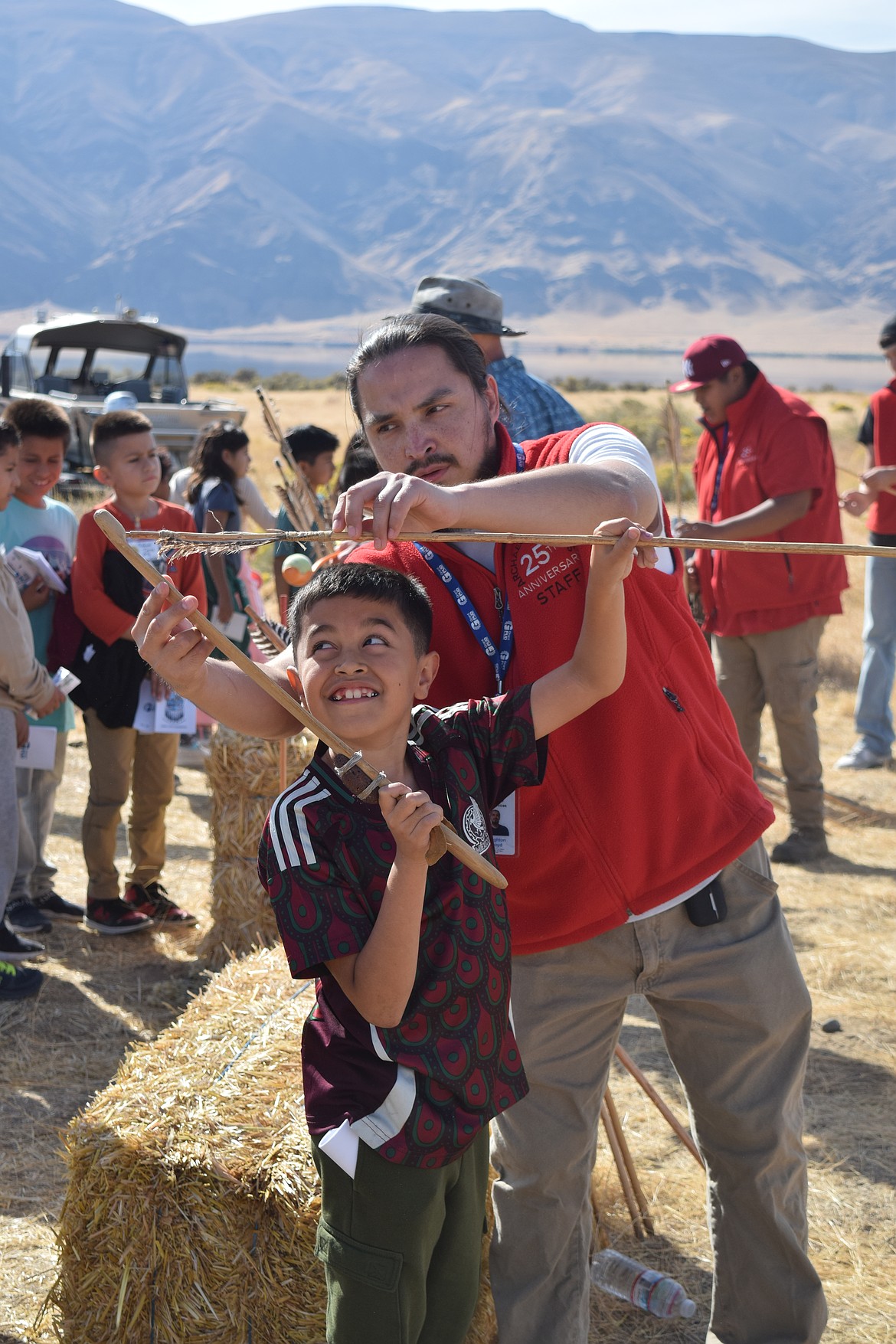 Leighton Boyd helps a student shoot an atlatl spear during the 25th annual archaeology days.