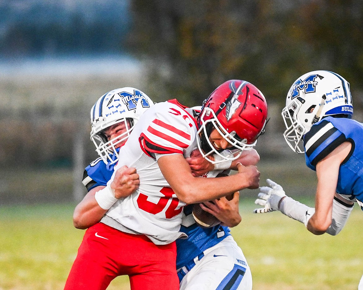 Mission's Kelby DuMont puts the squeeze on Arlee Warrior Eli O'Neill during last Friday's game, which netted the Bulldogs their fifth win of the season. (Christa Umphrey photo)