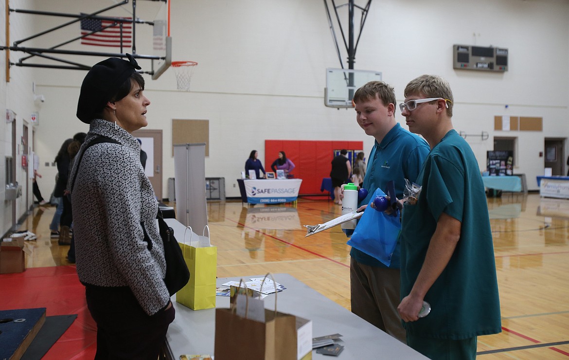 Esther Mann of Bella Angel Care chats with Project SEARCH interns Spencer Vogt, 18, center, and Durant Teague, 20, right, Wednesday evening during the Community Resource Fair at Venture Academy.