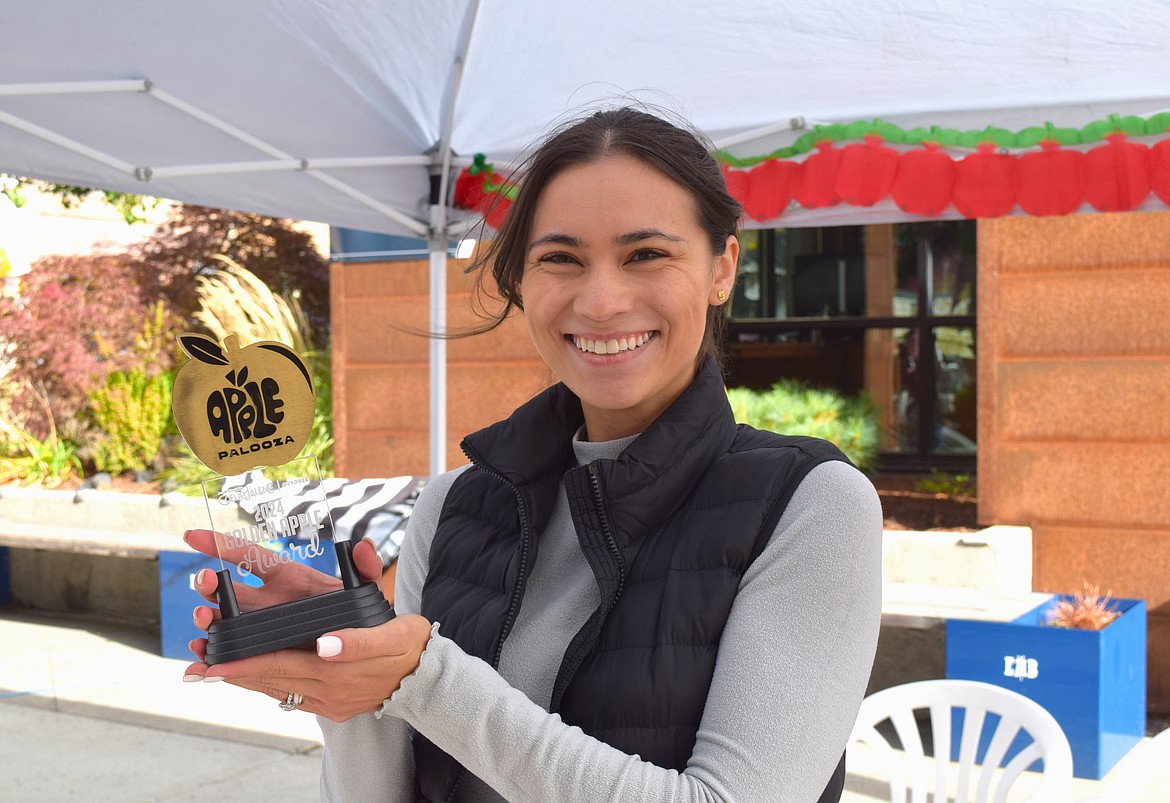 Mackenzie Macomber, marketing coordinator for the Downtown Coeur d’Alene Association, shows off this year's Golden Apple Award Saturday during Apple Palooza in Downtown Coeur d'Alene.