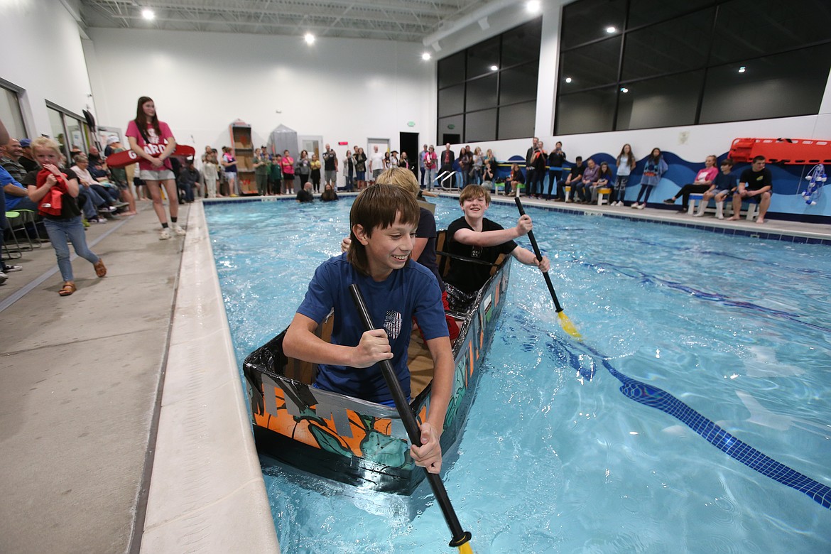 Keygan Chinchillas, front, Max Jasmine, center, and Ryon Young paddle their coffin-shaped boat during Woodland Middle School's cardboard boat races Monday evening at SafeSplash SwimLabs.