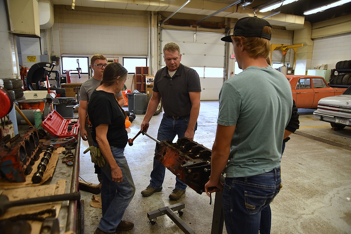 Flathead High School automotive teacher Rob Hunter, middle, assists Automotive 4 students Cole Butler, foreground, and Alan Johnson, in removing cam bearings from a small block in a Chevy 350  while volunteer Marlene Bauman watches on Wednesday, Oct. 9, 2024. (Hilary Matheson/Daily Inter Lake)