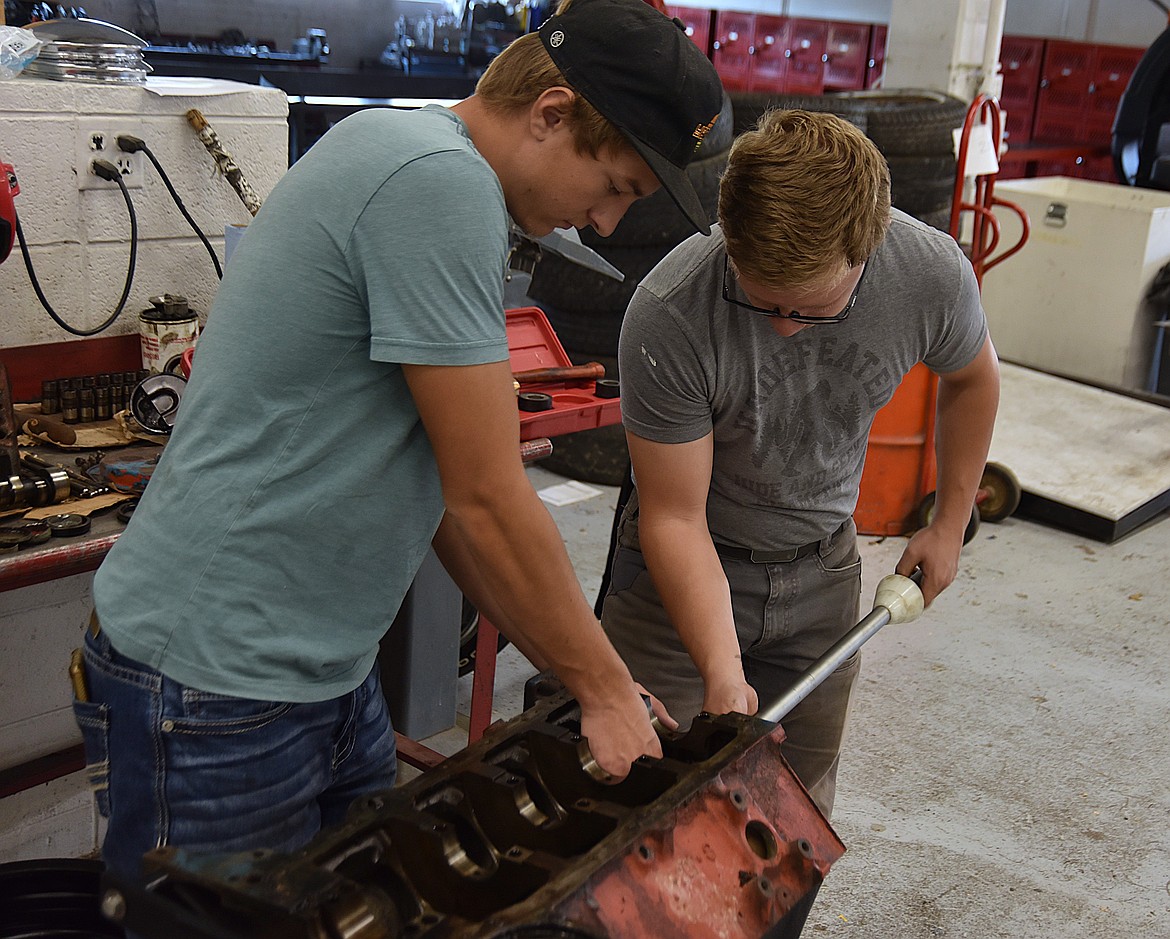 Flathead High School Automotive 4 students Cole Butler, left, and Alan Johnson, right, work to remove cam bearings from the small block of a Chevy 350 as part of their final project rebuilding a 1965 Studebaker in the shop on Wednesday, Oct. 9, 2024. Once the bearings are out Johnson said the parts will be washed to remove rust and debris. (Hilary Matheson/Daily Inter Lake)