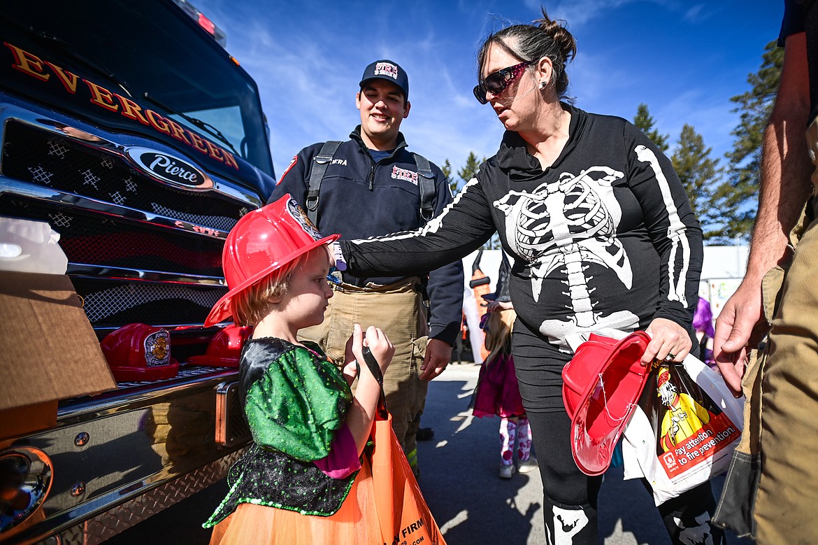 A young trunk-or-treater gets a fireman's helmet from firefighters with Evergreen Fire Rescue Station 81 at the Evergreen Trunk-or-Treat at the Kalispell Moose Lodge on Saturday, Oct. 26. (Casey Kreider/Daily Inter Lake)