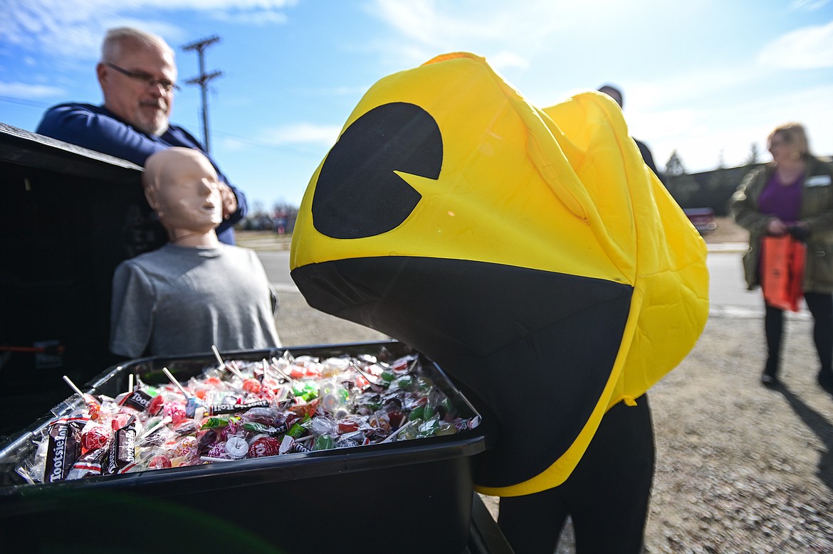 A young boy in a Pac-Man costume grabs candy from Don Weakly's Northwest Basic Life Support stand at the Evergreen Trunk-or-Treat at the Kalispell Moose Lodge on Saturday, Oct. 26. (Casey Kreider/Daily Inter Lake)