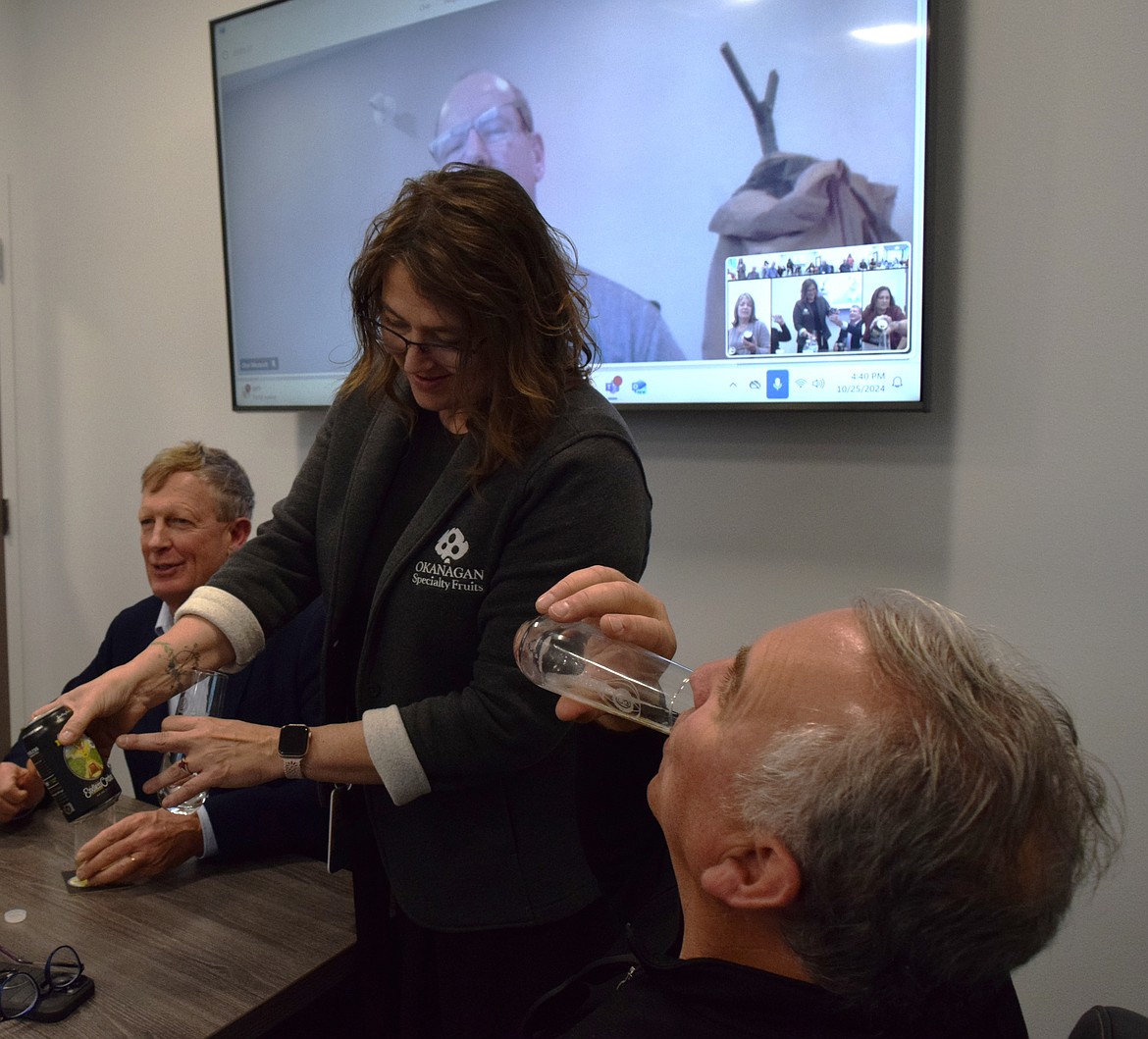 Alicia Devereux waits to pour a sample of the pineapple-mango cider as Mark Stennes finishes the last sample during the round table and cider sampling at Okanagan Specialty Fruits Friday. Everyone tried three ciders from the Endless Orchard brand – golden delicious, blueberry-basil and pineapple-mango.