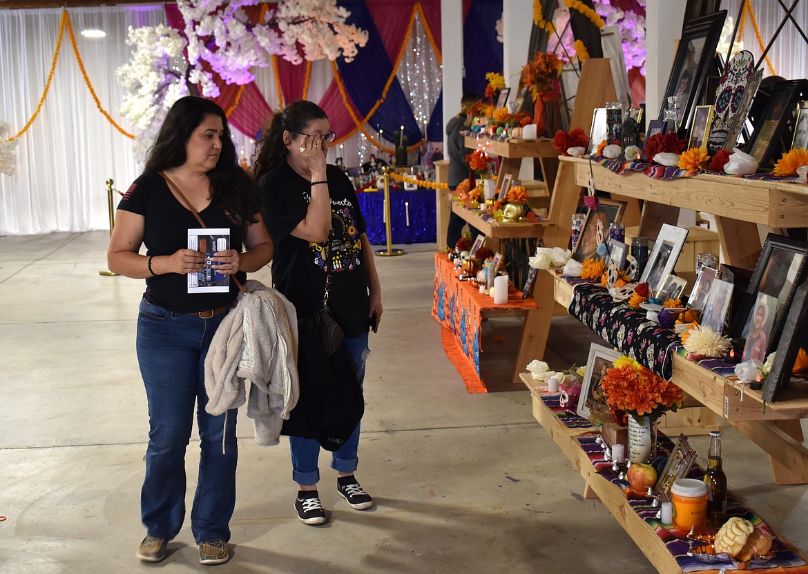 Crystal Hitt, left, and Vira Ortiz visit an ofrenda at the Moravida festival Saturday at the Grant County Fairgrounds. The ofrendas are shrines set up to remember family members who have passed on in the traditional Mexican Día de Muertos celebration.