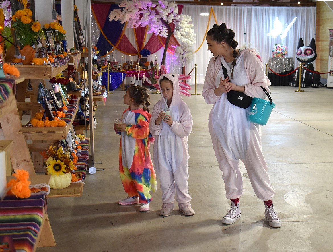 Julie Whitworth and her children Elle, 7 and Everett, 4, look over an ofrenda at the Moravida Festival Saturday. Many children came to the event in their Halloween costumes.