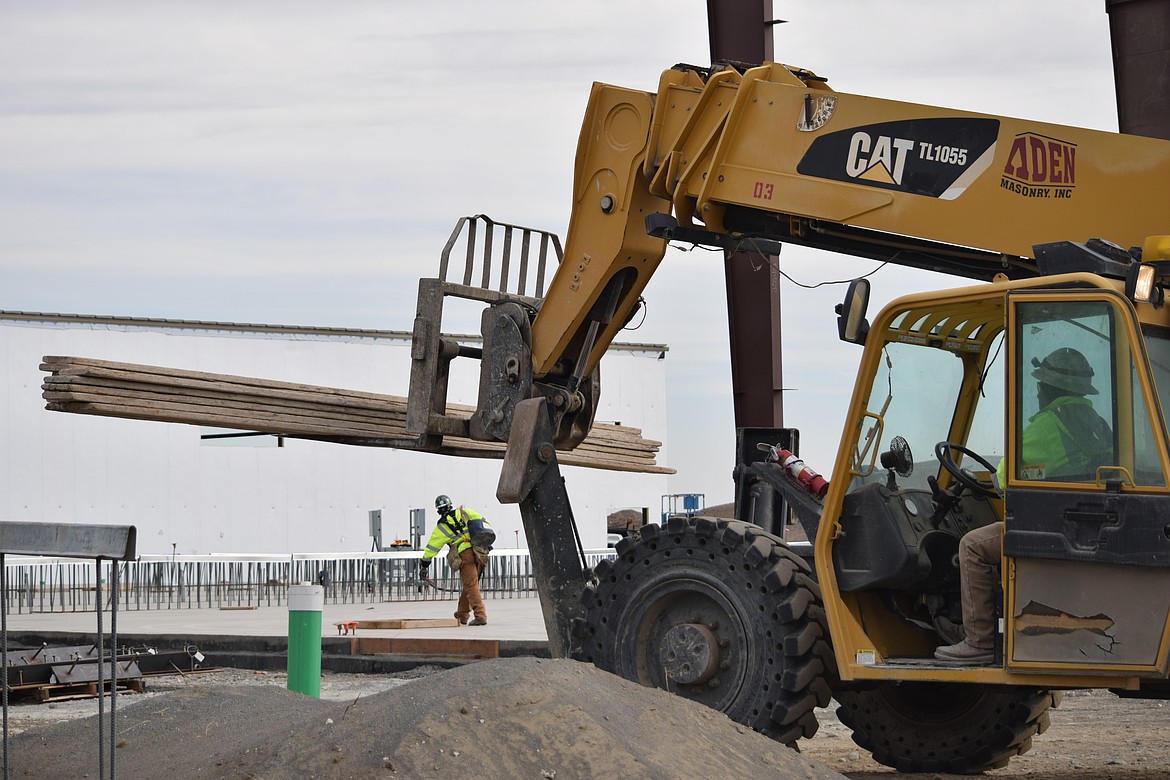 Crews move materials toward one of the slabs that will serve as the foundation for one of the two inmate housing blocs for the new Grant County Jail.