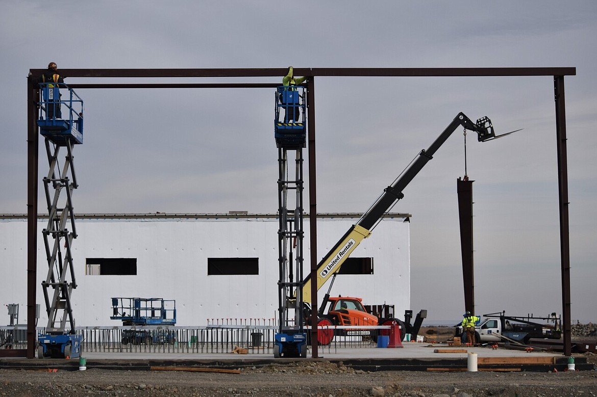 Lydig Construction workers install a crosspiece between steel supports for the second of two inmate housing buildings at the new justice center. The framework will be steel with larger girders like the one being lifted by the crane in the background supporting the building.