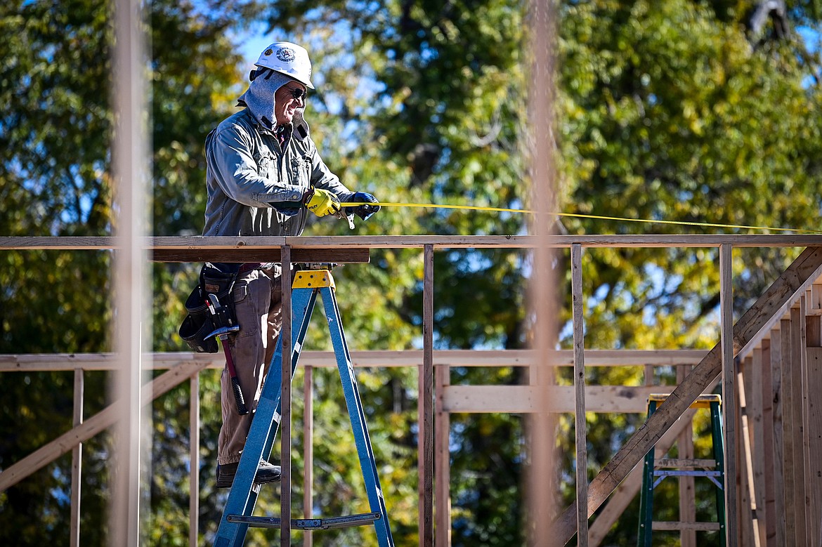 Volunteer Bruce Freeman measures for the second-floor wall frame of a duplex-style townhouse being built by Habitat for Humanity of Flathead Valley and Northwest Community Land Trust in Kalispell on Wednesday, Oct. 30. (Casey Kreider/Daily Inter Lake)