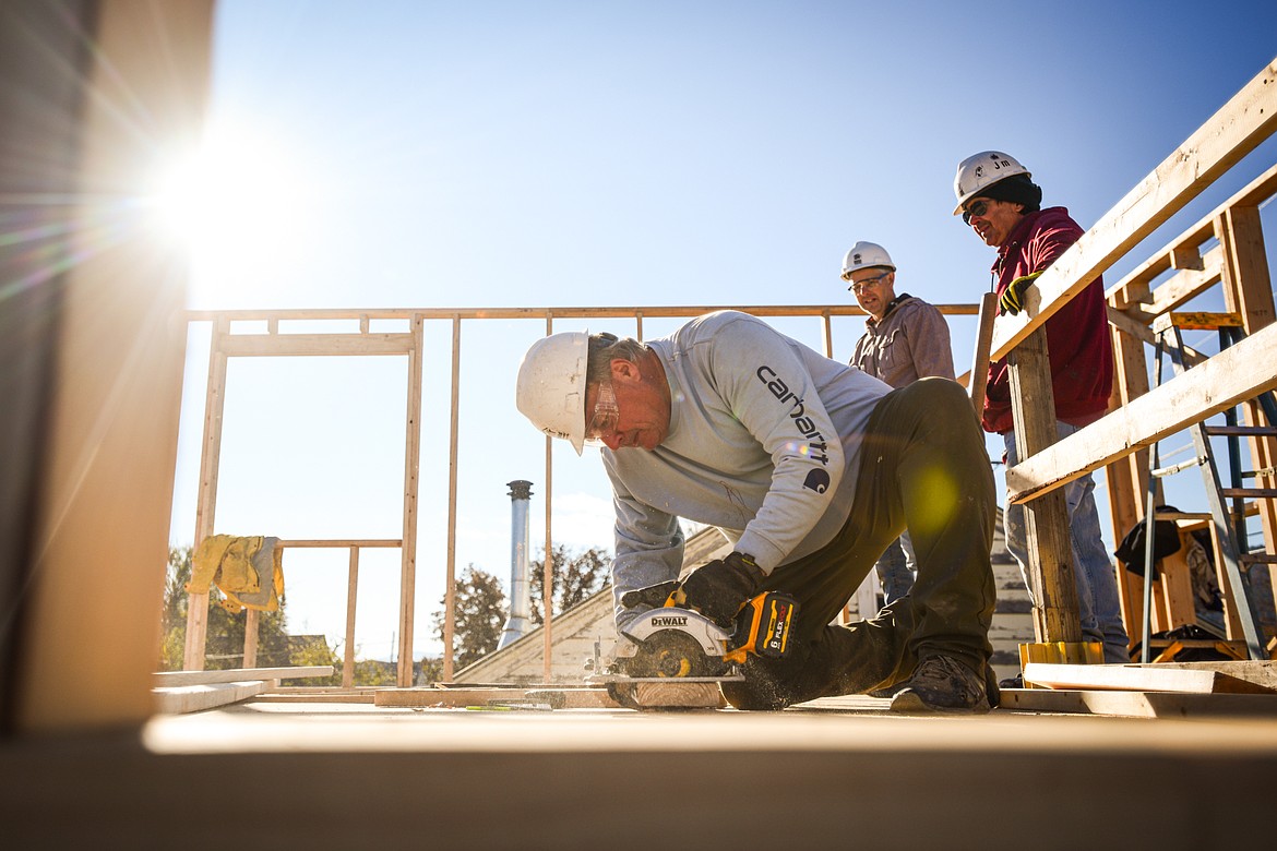 Volunteer Bill Rubly cuts boards for the second-floor wall frame of a duplex-style townhouse being built by Habitat for Humanity of Flathead Valley and Northwest Community Land Trust in Kalispell on Wednesday, Oct. 30. With Rubly are fellow volunteers Brian Putnam and Jim Poplin. (Casey Kreider/Daily Inter Lake)