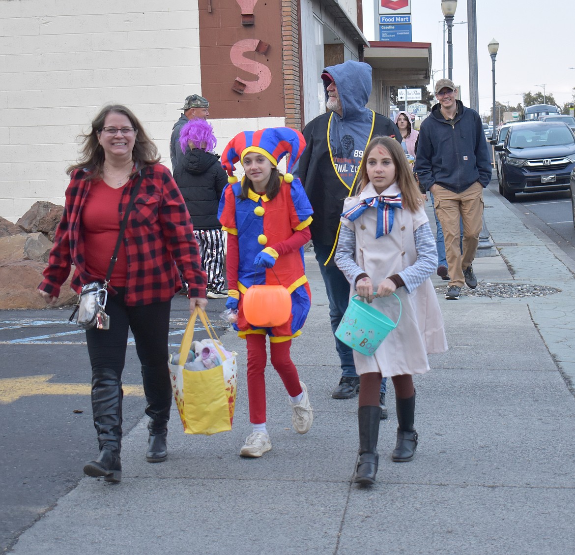 Ryann Harris, left, as Pomni from “The Amazing Digital Circus,” and Erica Harris, as M3gan, the terrifying doll from the movie of the same name, lead their parents Cathi Harris, left, and Ryan Harris through Ephrata’s downtown trick-or-treat event Thursday.