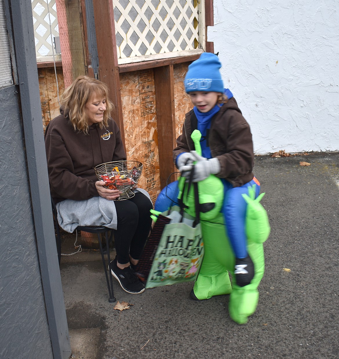 A green alien carries Kameron Shiflett, 7, to a bowl of candy at Ephrata’s downtown trick-or-treat event Thursday.