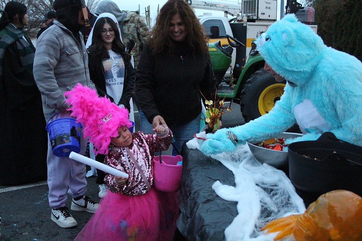 A very pink princess gets a treat from Taran Rosenberger, right, on the Downtown Trick or Treat walk Halloween night in Quincy.