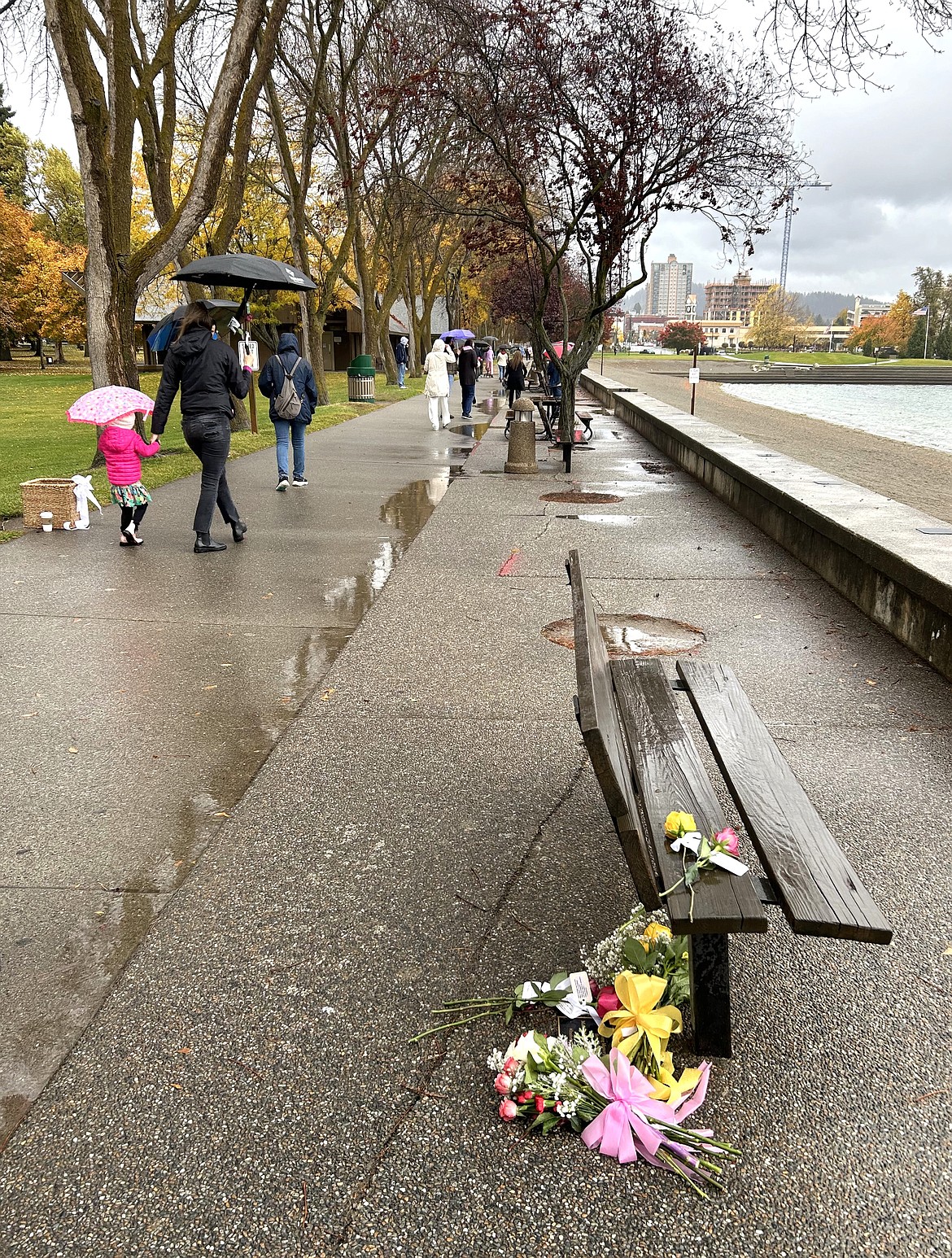 People leave flowers following the ceremony on Saturday for Madison Mogen, Kaylee Goncalves and Xana Kernodle at City Park.