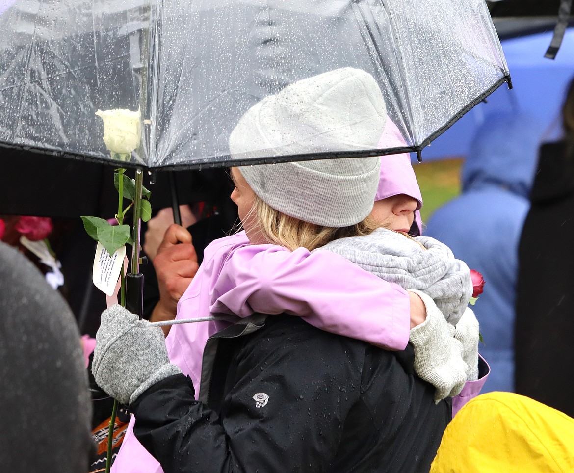 Two people share a hug during a ceremony in memory of Maddie Mogen, Kaylee Goncalves and Xana Kernodle at City Park on Saturday.