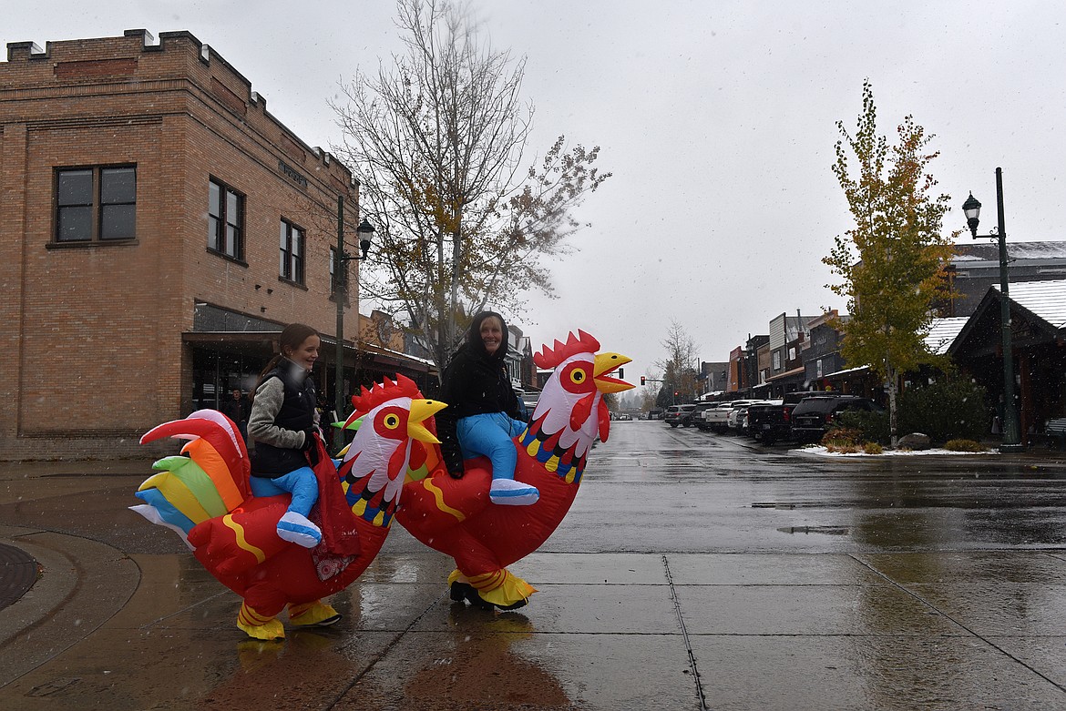 Caton Fought and her grandmother Cindy Miner cross the road mounted on chickens on Halloween. (Kelsey Evans/Whitefish Pilot)