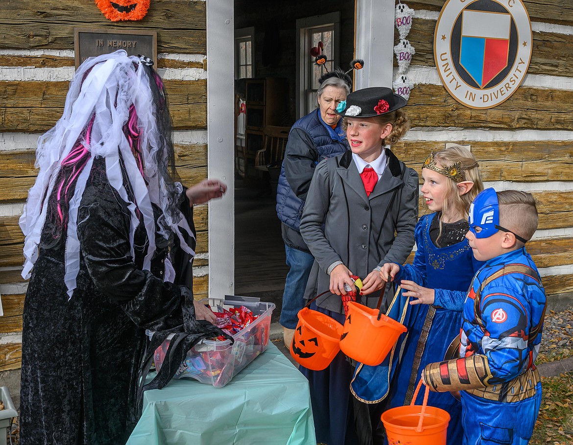 Plains Woman's Club member Debbi Kirseh Baun passes out candy to Avla Rehbein, Emma Rehbein and Wyatt Rehbein. (Tracy Scott/Valley Press)