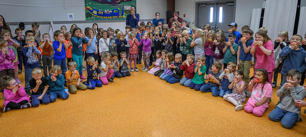 Kindergarten through third grade students in Plains take a bit out of their apples. (Tracy Scott/Valley Press)