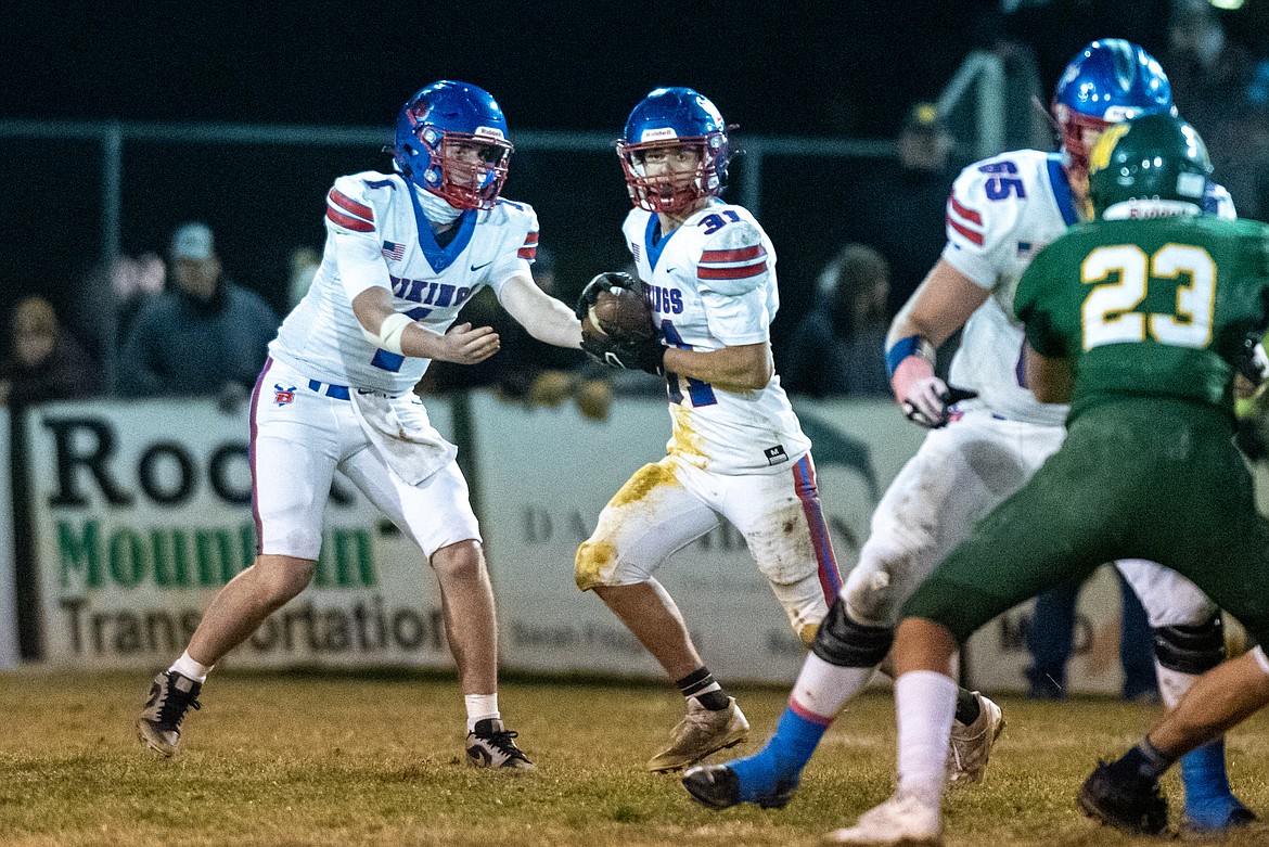 Cole Schmit hands off to Treker Hickey playing Whitefish Friday. (Avery Howe/Bigfork Eagle)