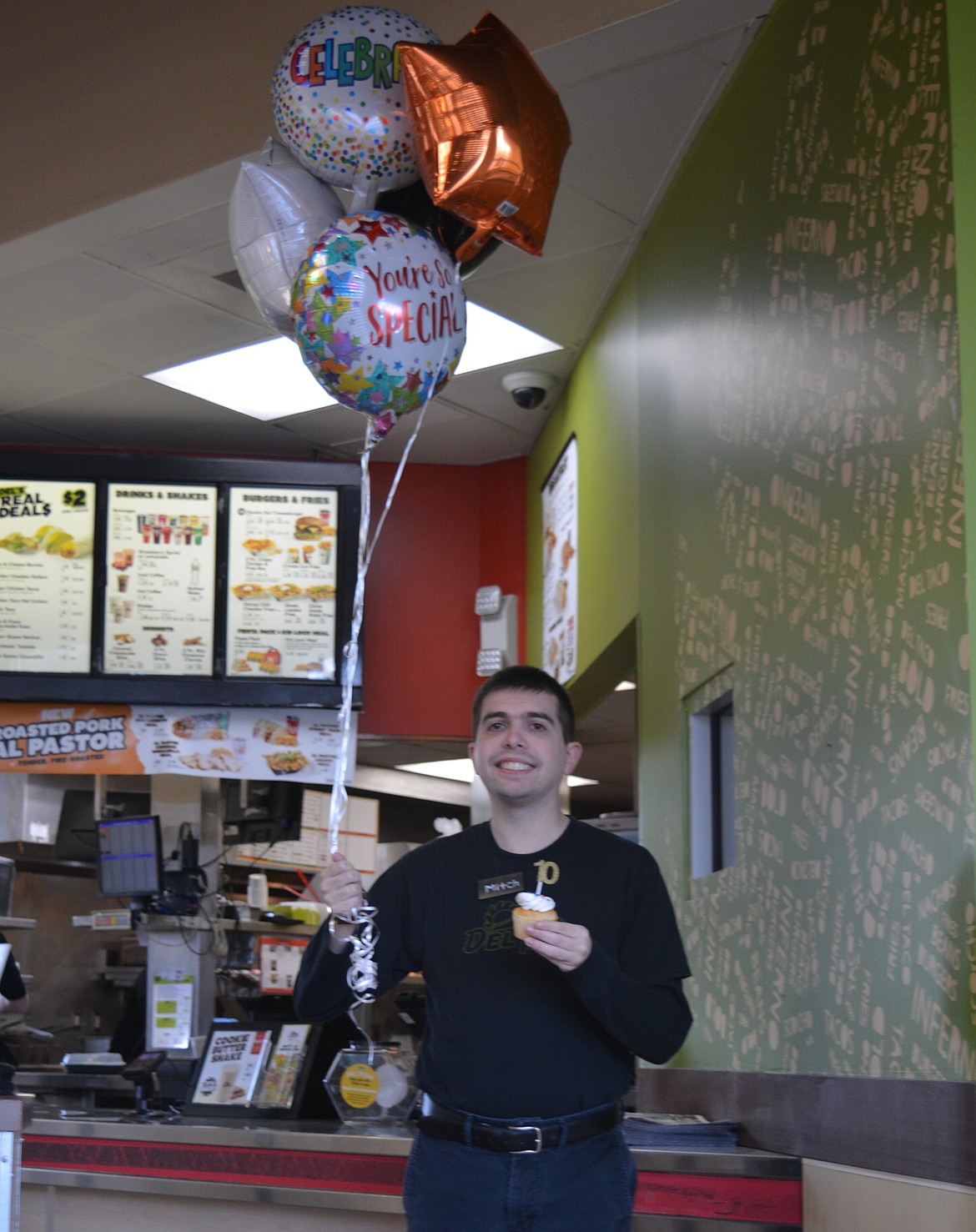 Mitch Loisel shows off the cupcakes he brought to share with coworkers and the balloons he received before starting his shift at Del Taco on Tuesday.