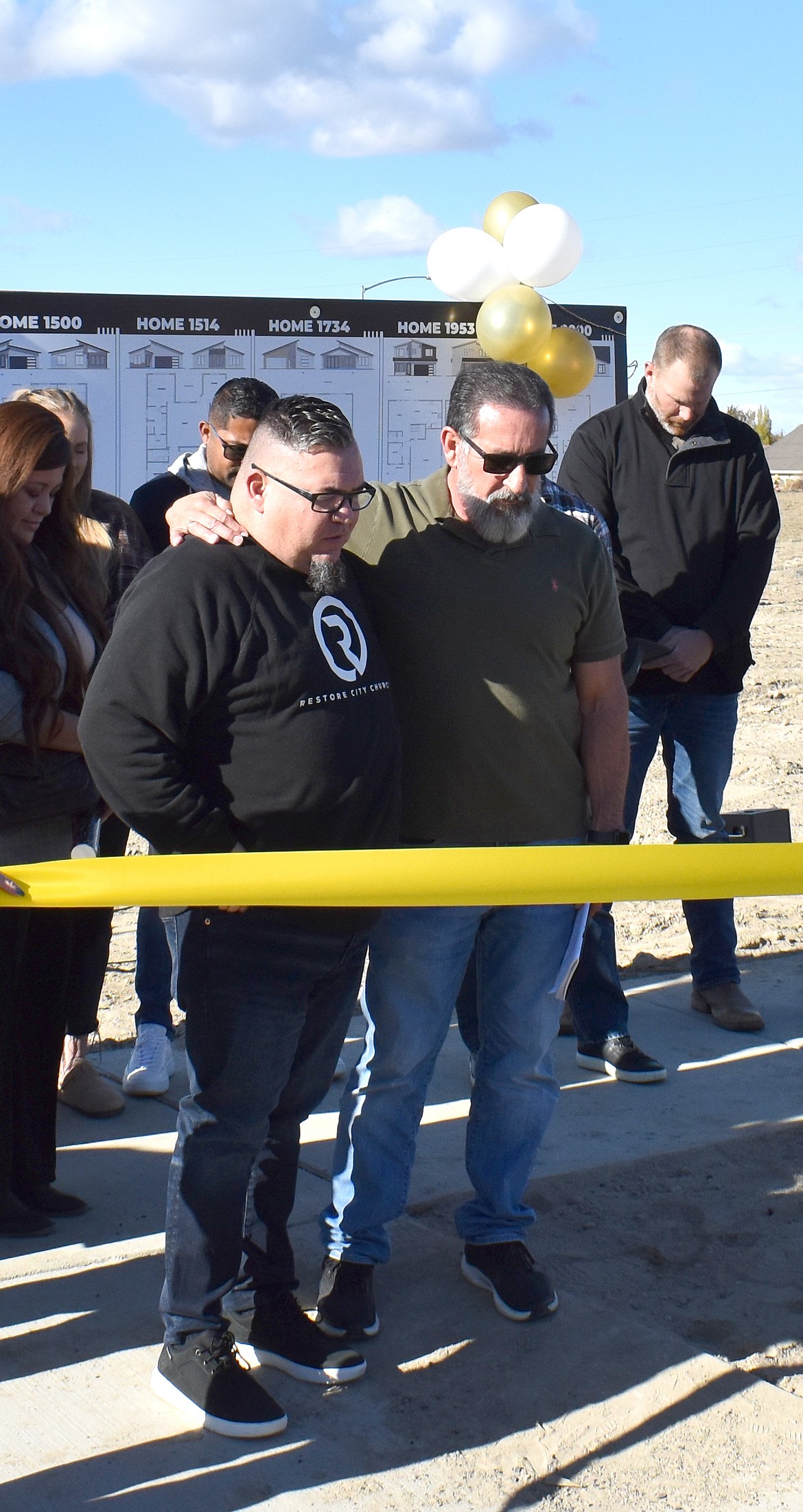 Pastor Mike Alvarado, left, of Restore City Church in Moses Lake prays with Palos Verdes CEO Angel Garza, asking for peace for the Palos Verdes at Lakemont neighborhood and the city of Moses Lake.