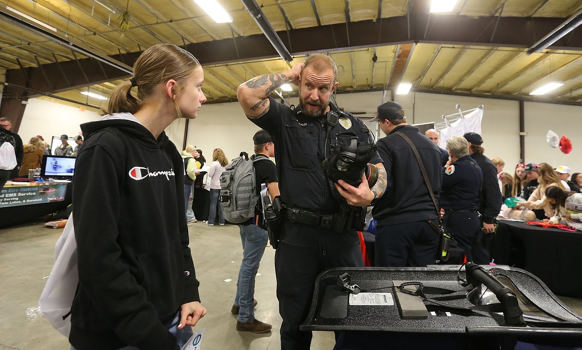 Post Falls Police Capt. Jason Mealer demonstrates for Lakeland Middle School eighth grader Mikayla Turner how to use a gas mask as they participate Wednesday in the Unlock Your Future career planning event at the fairgrounds.